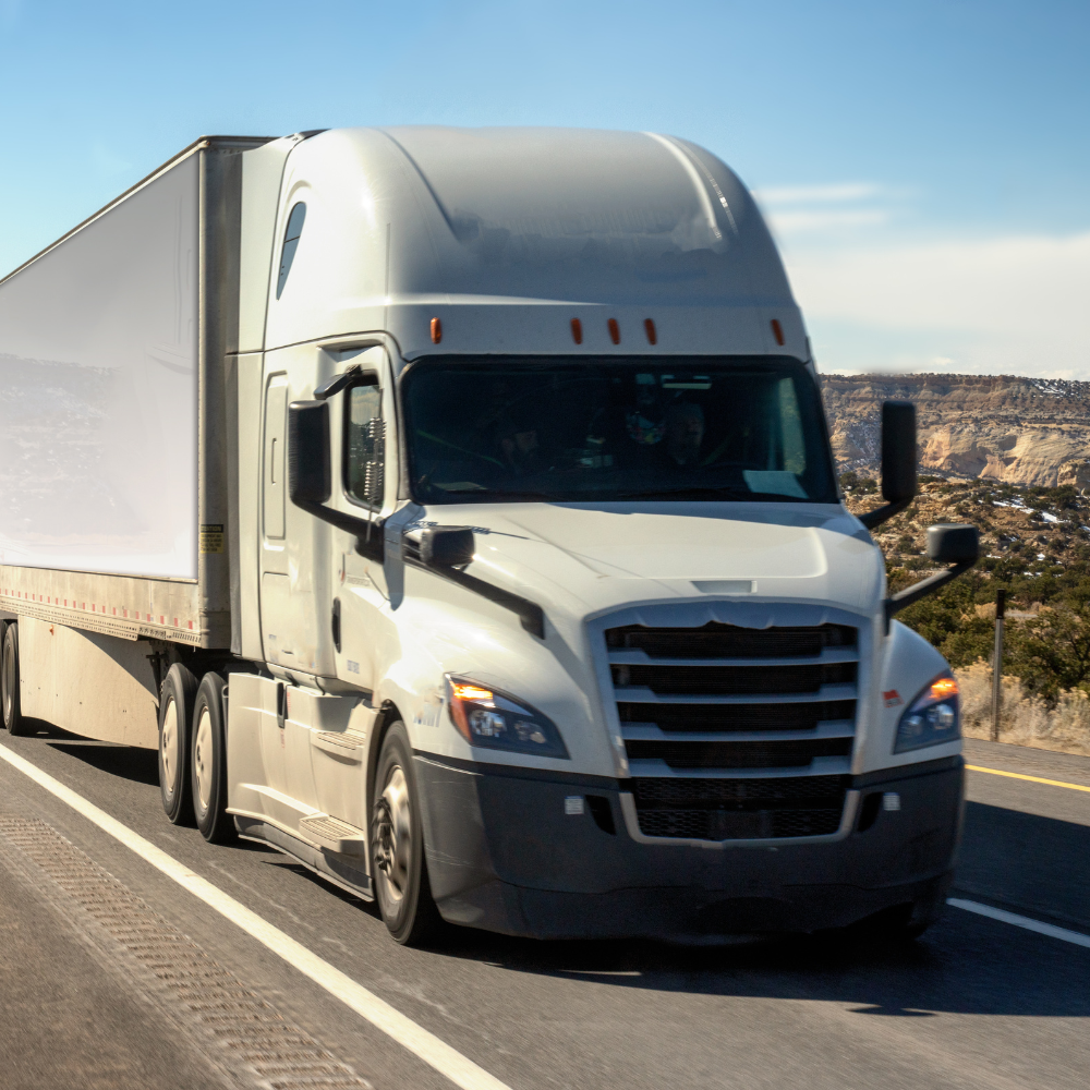 White freight truck driving on rural highway during the day