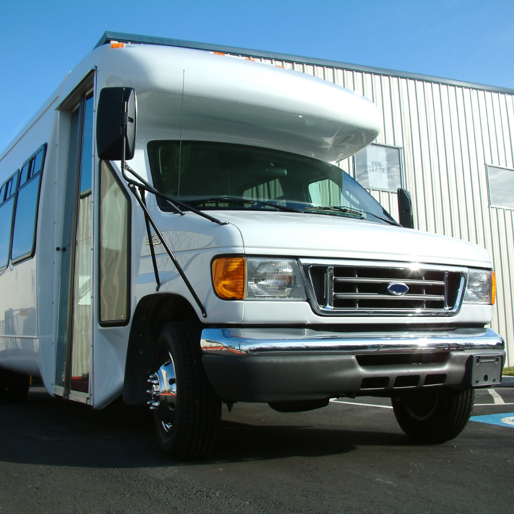 White transit shuttle bus parked at dispatch facility during the day